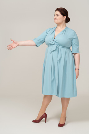 一个穿蓝色裙子的女人的前视图，伸出手来握手