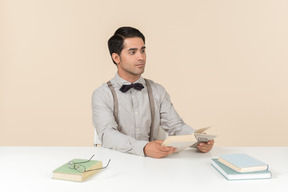 Profesor sentado a la mesa y leyendo libros