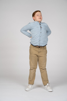 Vista frontal de un niño de pie con las manos en la espalda