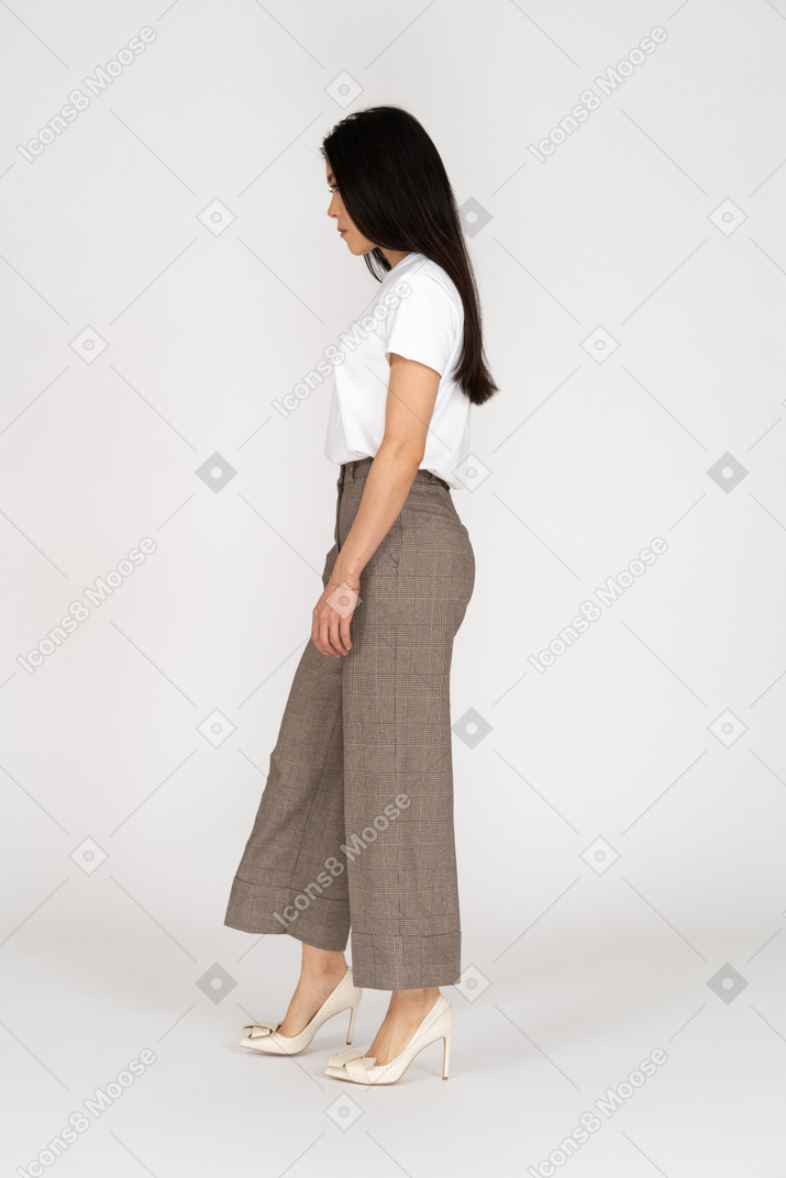 Vista laterale di una giovane donna in calzoni e t-shirt guardando verso il basso