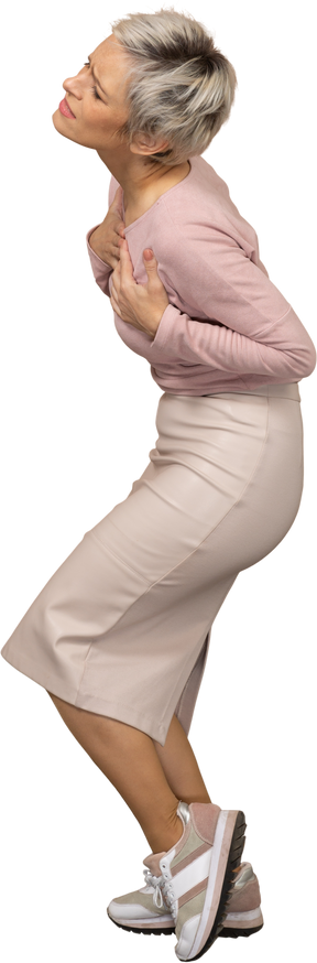 Vista lateral de uma mulher chateada em roupas casuais em pé com as mãos no peito