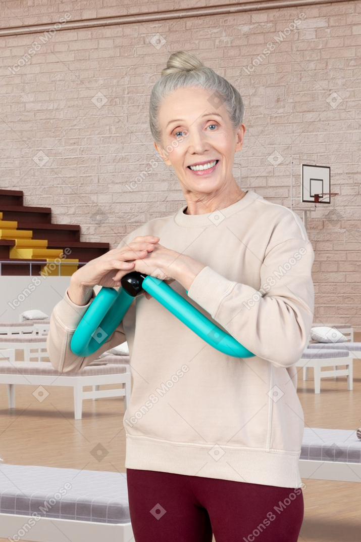 Woman holding an arm exerciser in a room with beds