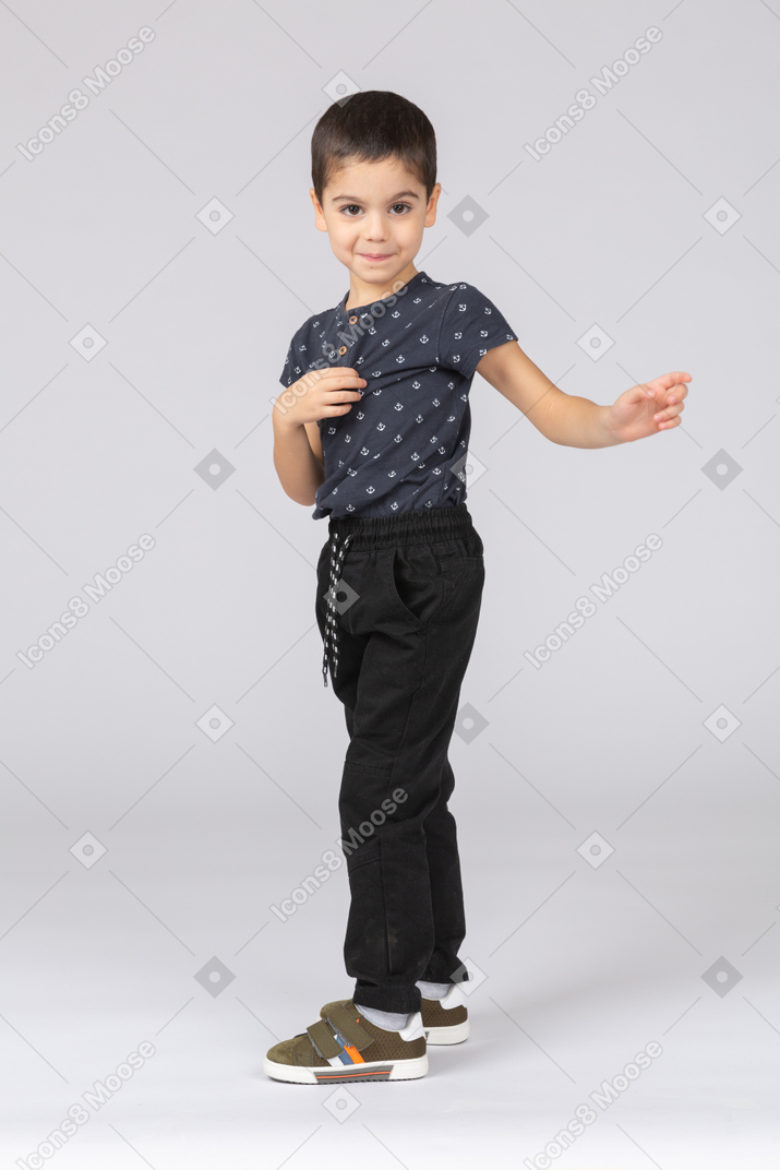 Side view of a cute boy looking at camera and pointing with finger