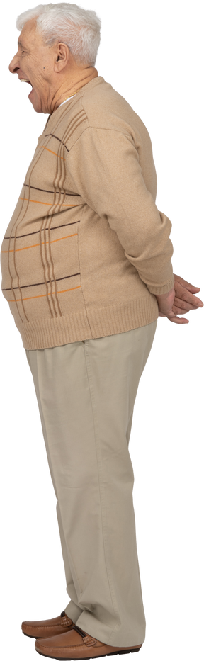 Vista lateral de un anciano con ropa informal de pie con las manos detrás de la espalda