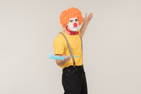 Male clown in red wig using balloon as a sword