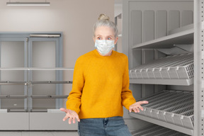 A woman wearing a face mask standing in front of shelves