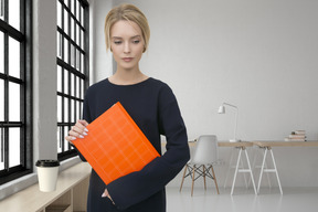 Pensive woman holding orange folder