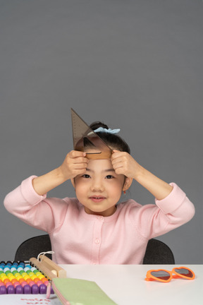 Smiling little girl holding up a triangle ruler