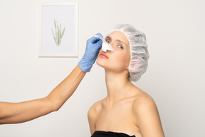 Doctor removing medical plaster from woman's nose