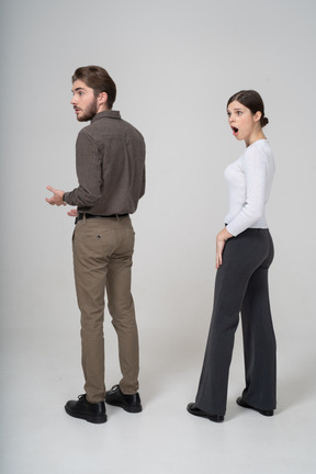 Three-quarter back view of an astonished young couple in office clothing