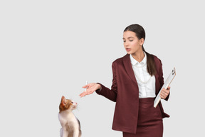 A woman standing next to a cat and holding a clipboard