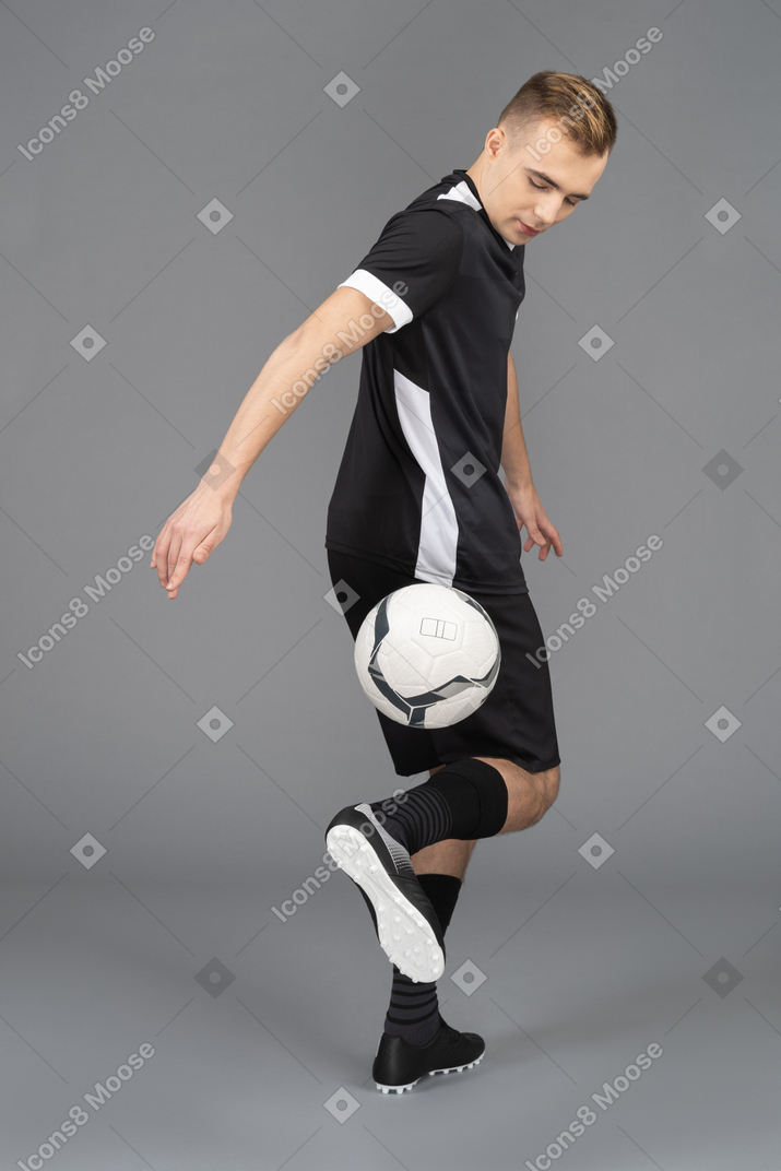 Full-length of a male football player turning away and kicking a ball