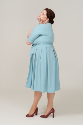 Vue latérale d'une femme en robe bleue posant