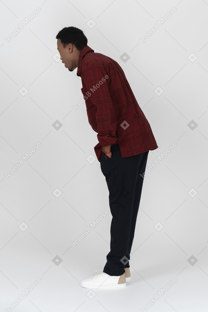 Side view of young man bending down and looking at something