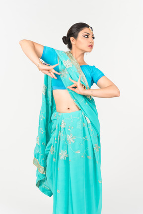 Joven mujer india en sari azul de pie en posición de baile