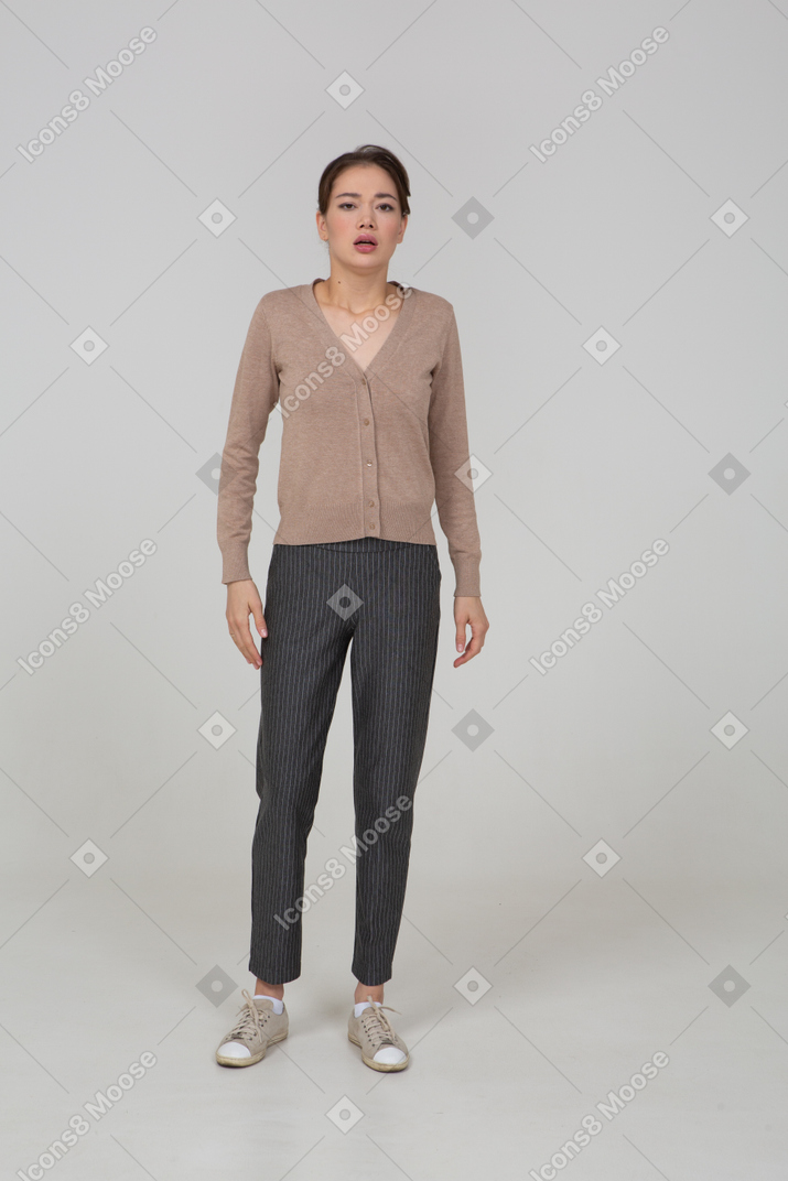 Vista frontal de una joven en suéter y pantalones tomando una respiración profunda