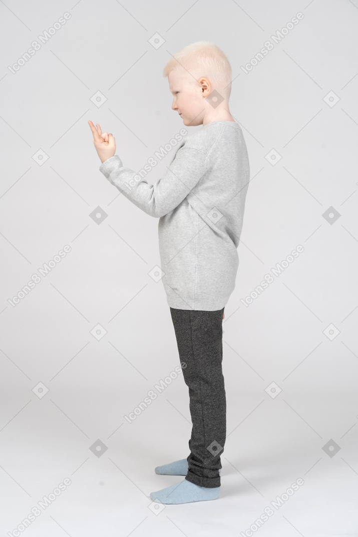 Vista lateral de um menino fazendo um sinal de rock