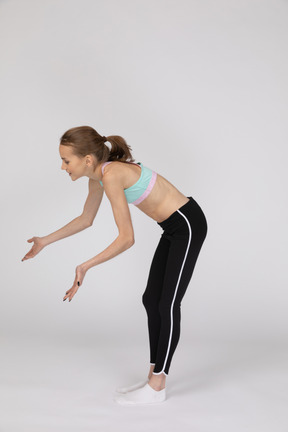 Side view of a teen girl in sportswear raising hand and arguing