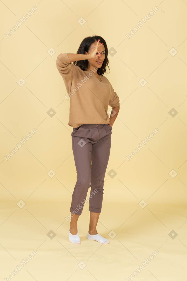 Three-quarter view of a dark-skinned cheerful young female showing ok gesture
