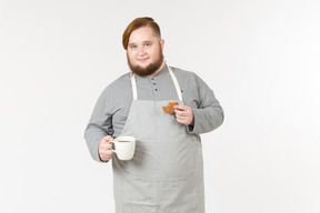 Ein dicker mann mit einem keks und einer tasse kaffee