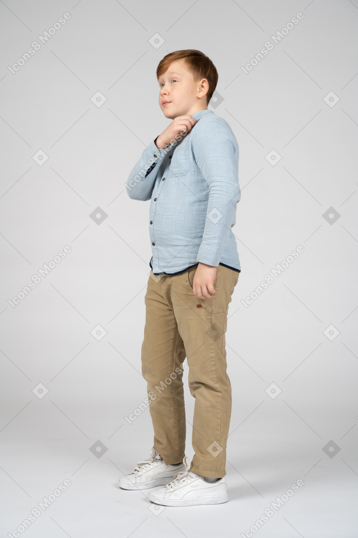 Side view of a cute boy standing with hand on shoulder
