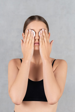 Mulher segurando almofadas de algodão nos olhos