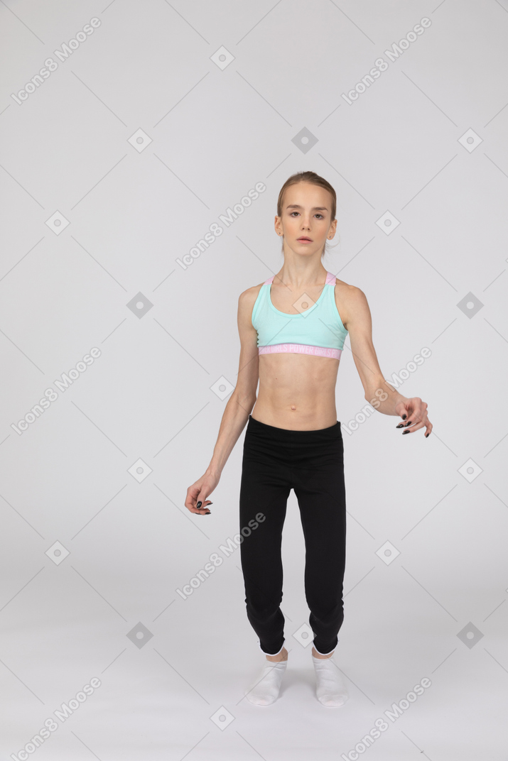 一个十几岁的女孩，蹲着，看着相机的运动服的前视图