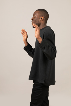 Side view of a young man with raised hands