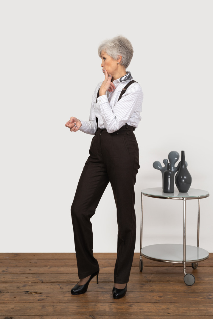 Front view of an old lady in office clothing touching her face