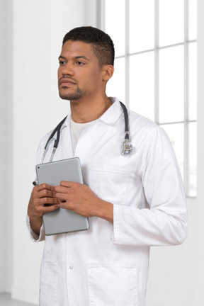 A man in a white lab coat holding a tablet