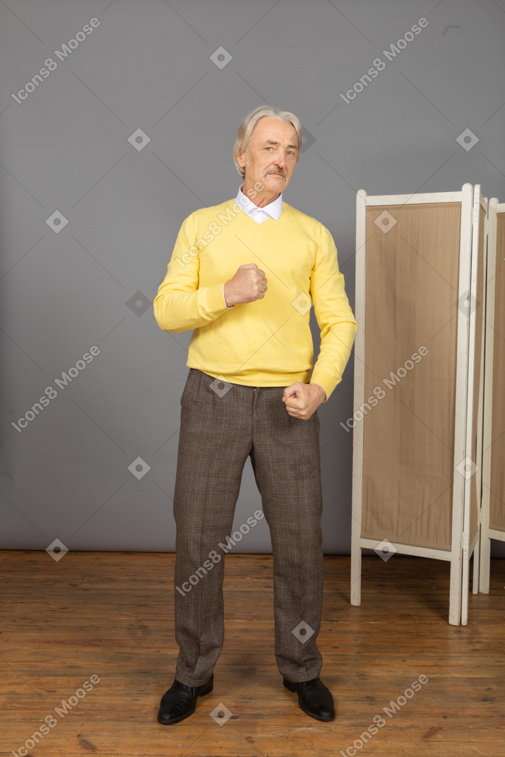 Front view of an old strong man clenching fists