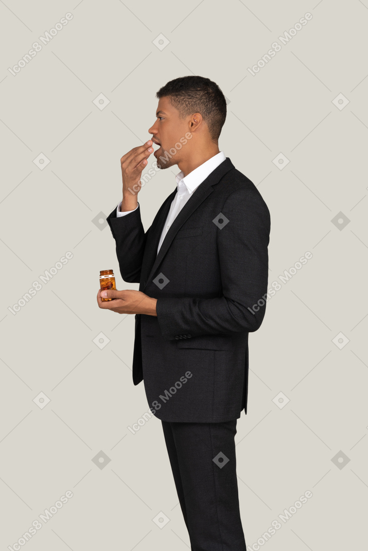 African american male in black suit taking pills