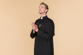 Catholic priest praying with eyes closed using prayer beads