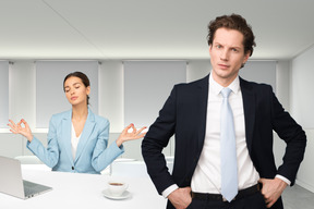 The woman relaxing at working place and the man is standing near her with hands in his pockets