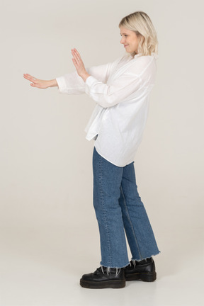 Side view of a blonde female outstretching arms and grimacing