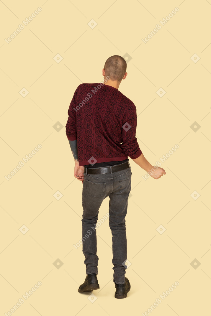 Vista posteriore di un giovane uomo che balla vestito con un pullover rosso