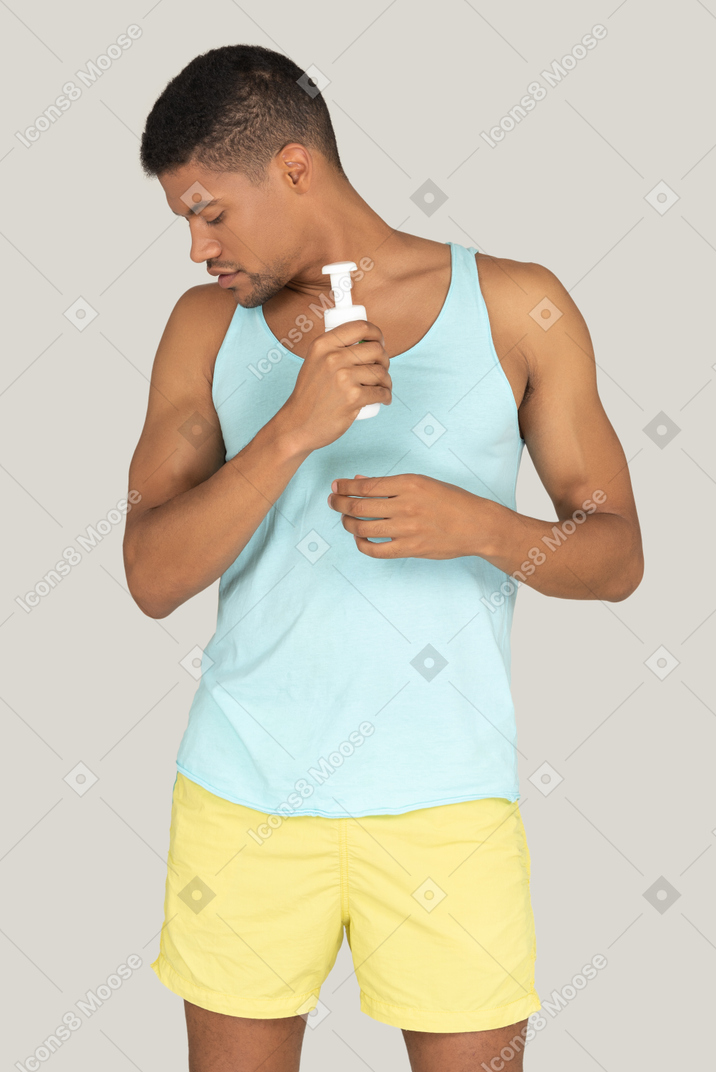 Young man in tank top looking at his biceps