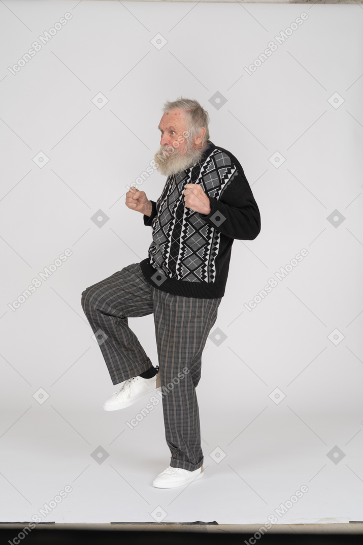 Senior man with clenched fists standing on one leg