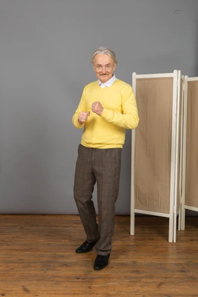 Front view of a smiling old man clenching fists