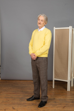 Three-quarter view of an old man holding hands together while standing still