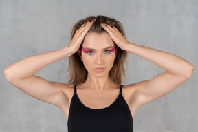 Portrait of a young woman with bright eye make-up pulling up her hair