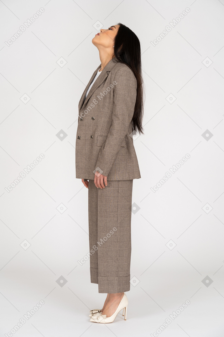Side view of a young lady in brown business suit throwing head back
