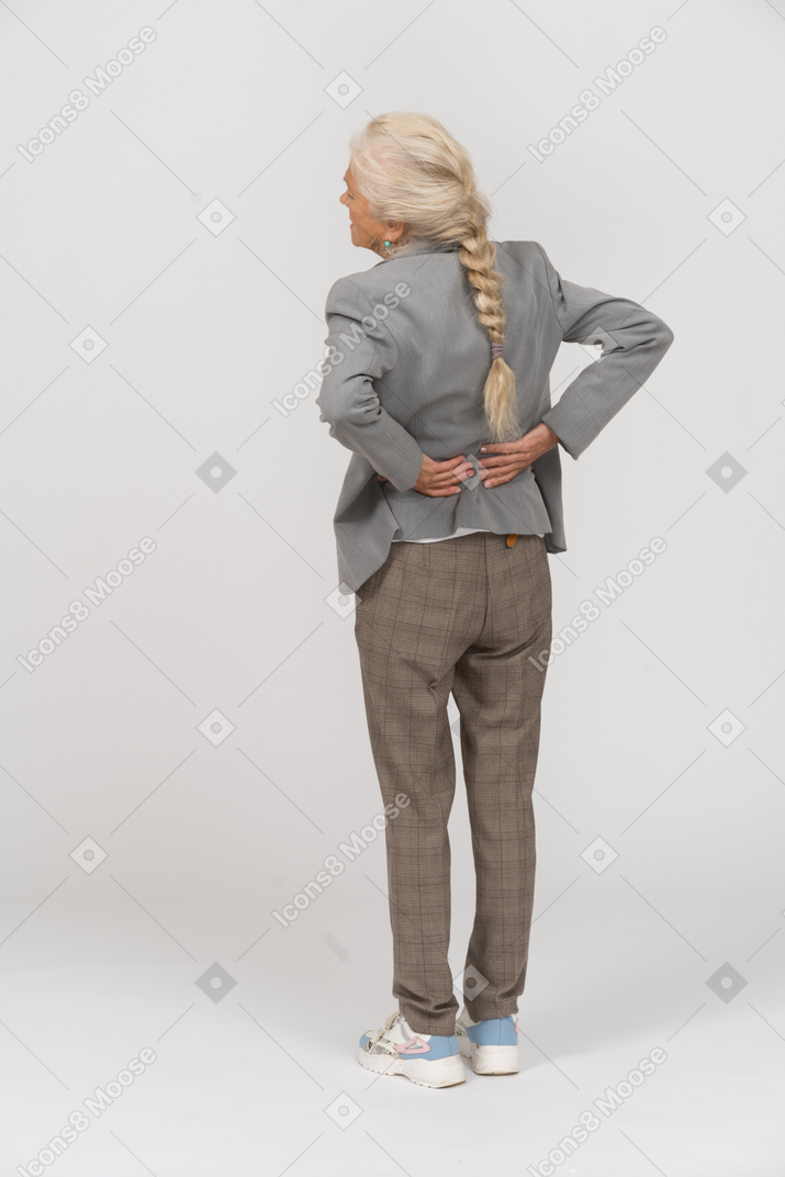 Вид сзади пожилой женщины в костюме, страдающей от боли в спине