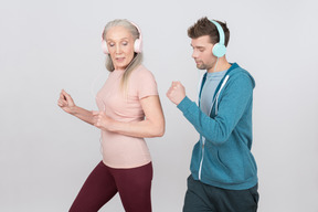 Anciana y chico joven usando auriculares y corriendo