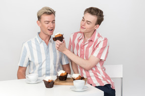 Beau jeune homme donnant un petit gâteau à son partenaire