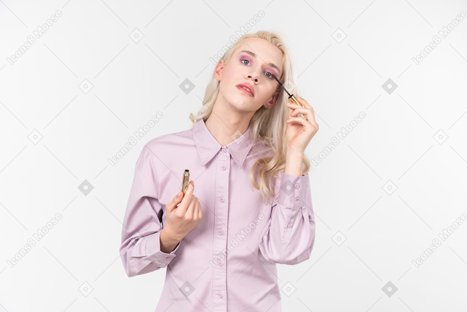Young blond-haired person in a pastel violet shirt, doing their makeup