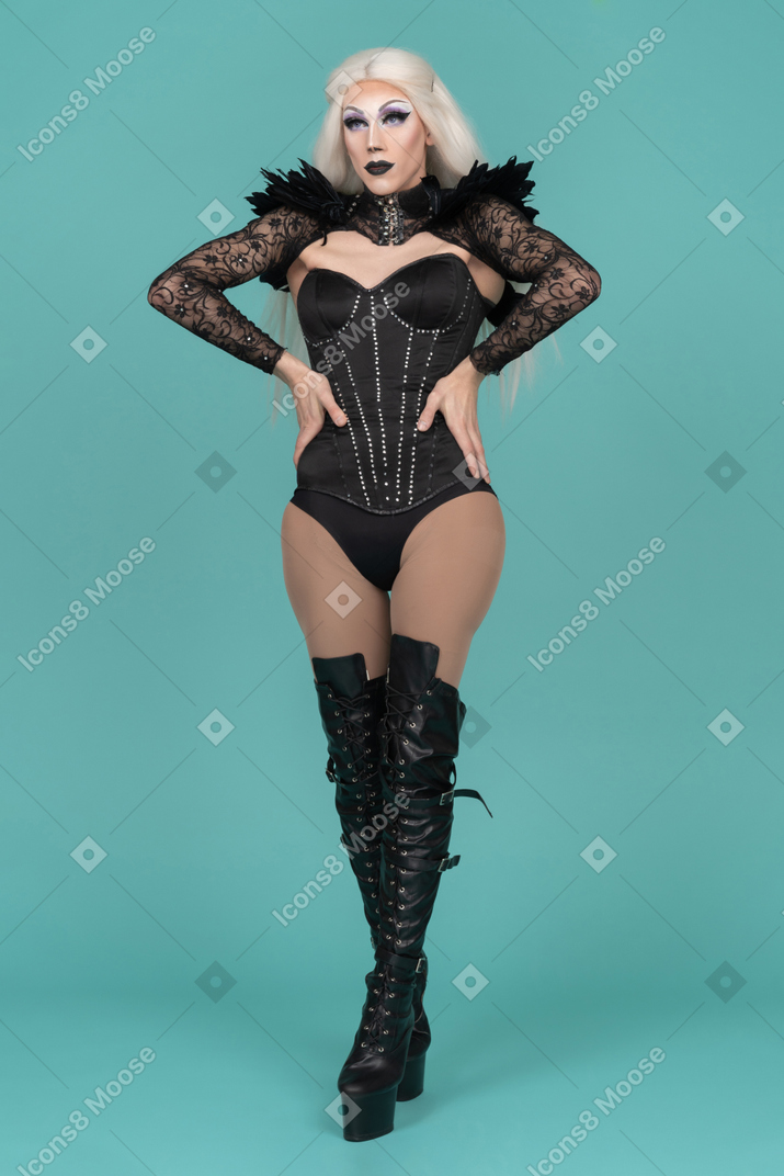 Transvestite standing with hands on hips and elbows pointing forward