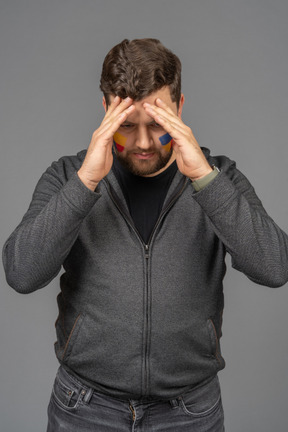 Front view of a puzzled male football fan touching head