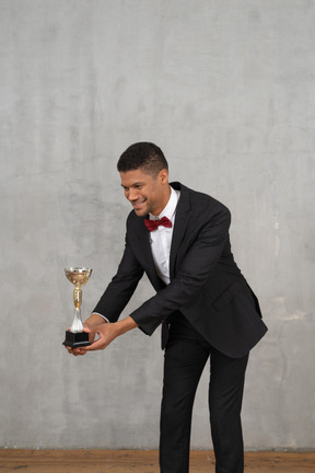 Man in suit presenting an award to someone small