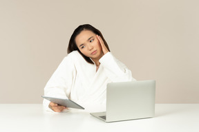 Надоело молодая азиатская женщина разговаривает по телефону, держит планшет и делает покупки в интернете